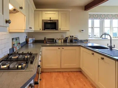 a kitchen with white cabinets and a sink and a stove at Squirrel Cottage in Keswick