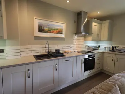 a kitchen with white cabinets and a sink at Fox Howe in Keswick