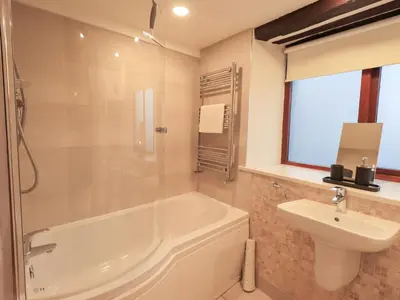 a bathroom with a bath tub and a sink at Jasmine Cottage in Keswick