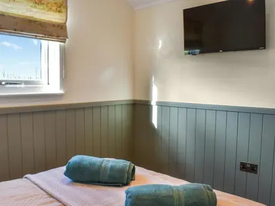 a bedroom with a bed with a flat screen tv on the wall at Meadows View Shepherd's Hut in Cockermouth