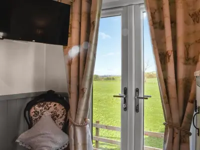 a window with a view of a green field at Meadows View Shepherd's Hut in Cockermouth