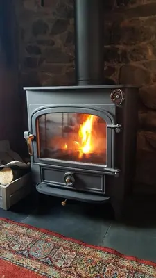 a wood stove in a room with a fire in it at Rose cottage on the peaceful solway coast in Port Carlisle