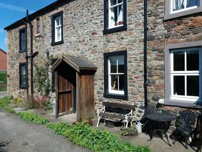 a brick building with a wooden door and a bench at Rose cottage on the peaceful solway coast in Port Carlisle