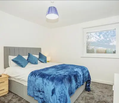 a bedroom with a bed with a blue blanket on it at Caul View Apartment in Dumfries