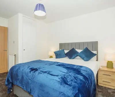 a bedroom with a large blue bed with blue pillows at Caul View Apartment in Dumfries