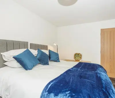 a bedroom with a large bed with blue pillows at Caul View Apartment in Dumfries