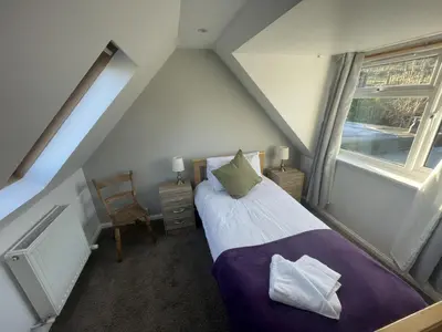a attic bedroom with a bed and a window at Campbell Cottage in Biggar