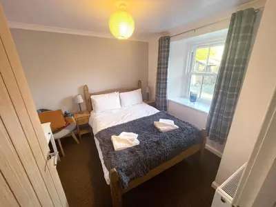 a bedroom with a bed with two towels on it at Campbell Cottage in Biggar