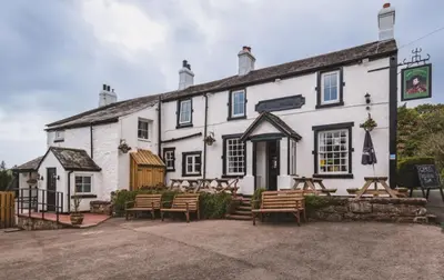 a white building with benches in front of it at King George IV Inn in Eskdale