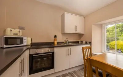 a kitchen with white cabinets and a table and a microwave at King George IV Inn in Eskdale