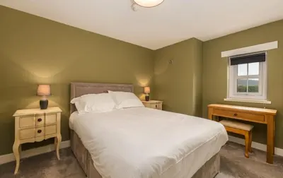 a green bedroom with a bed and a window at King George IV Inn in Eskdale