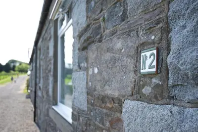 a stone wall with a sign on the side of a building at Meadow Cottage in Girthon