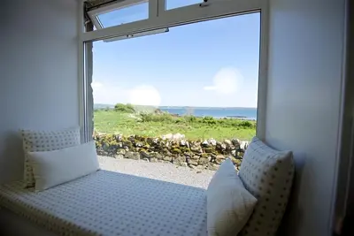 a room with a window looking out at the ocean at Meadow Cottage in Girthon