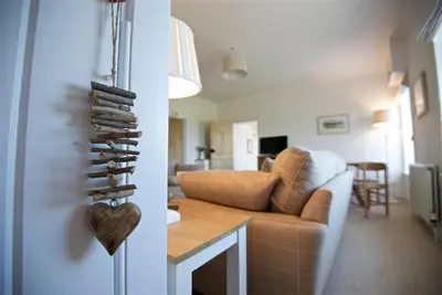 a living room with a heart hanging on a wall at Meadow Cottage in Girthon