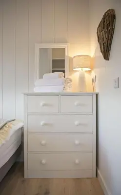 a dresser with a mirror and a lamp on it at Muir Lodge in Gatehouse of Fleet