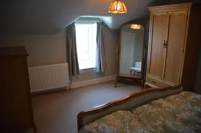 a bedroom with a bed and a dresser and a mirror at Munro Cottage in Rockcliffe