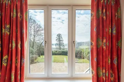 a window with red curtains in a room at Ornockenoch House in Gatehouse of Fleet