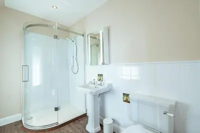 a white bathroom with a shower and a sink at Ornockenoch House in Gatehouse of Fleet