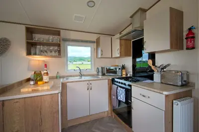 a small kitchen with a sink and a stove at Pebbles in Girthon
