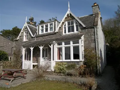 an old stone house with a picnic table in front of it at Rocklea in Kippford