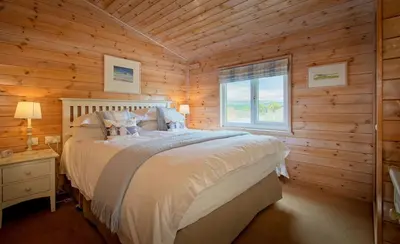 a bedroom with a bed in a wooden cabin at The Buoys in Girthon