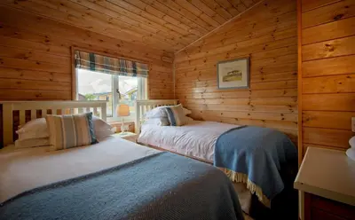 a bedroom with two beds in a log cabin at The Buoys in Girthon