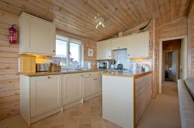 a kitchen with white cabinets and a wooden ceiling at The Buoys in Girthon