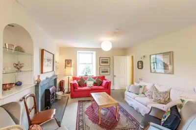 a living room with a red couch and a red chair at The Miller's House in Castle Douglas