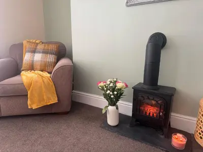 a living room with a wood stove and a chair at The Hidden Hicks - Sleeps 2 in Whitehaven
