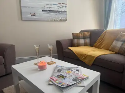 a living room with a coffee table with a newspaper and candles at The Hidden Hicks - Sleeps 2 in Whitehaven