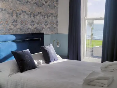 a bedroom with a bed and a window with the ocean at Kings House in Douglas