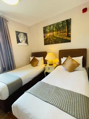 a hotel room with two beds and a lamp at Fairlight Guesthouse in Glenridding