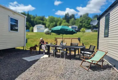 a woman sitting at a table with an umbrella at 5 lochview in Beattock