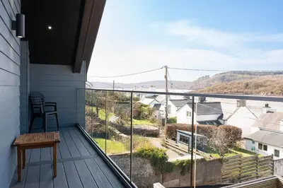 a balcony with a table and a view of the countryside at 2 Kippford Slipway in Kippford