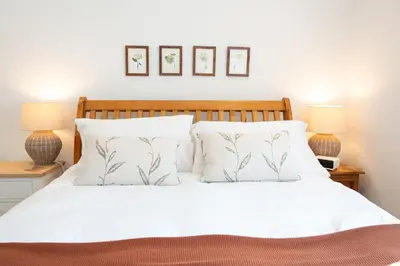 a bedroom with a white bed with two lamps at 2 Kippford Slipway in Kippford