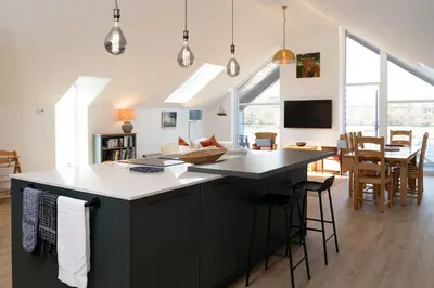 a kitchen with a black island and a dining room at 2 Kippford Slipway in Kippford