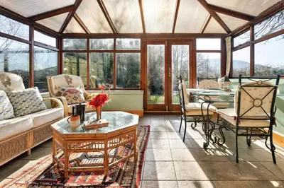 a conservatory with a couch and a table and chairs at Finest Retreats - St Francis Cottage in Ulpha
