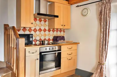 a small kitchen with a stove and a microwave at Finest Retreats - St Francis Cottage in Ulpha