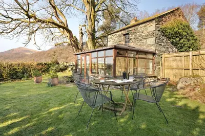 a table and chairs in a yard with a house at Finest Retreats - St Francis Cottage in Ulpha