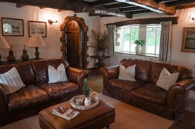 a living room with leather couches and a table at Riverside Country House and Cottage in Sunderland