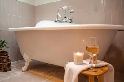 a bathtub in a bathroom with a candle and a candle at Riverside Country House and Cottage in Sunderland