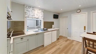 a large kitchen with white cabinets and a window at Stanley House in Bassenthwaite