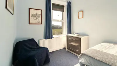 a bedroom with a bed and a window with a chair at Stanley House in Bassenthwaite