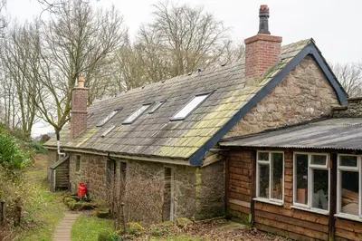 an old stone house with skylights on the roof at Gardeners Cottage in Auchencairn