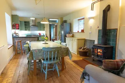 a kitchen and dining room with a table and a stove at Gardeners Cottage in Auchencairn