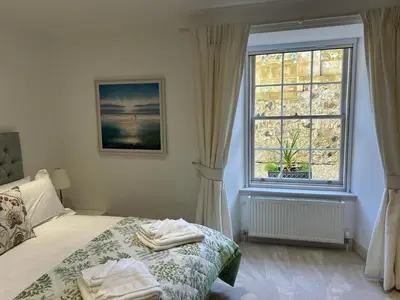 a bedroom with a bed and a large window at Underwood House Garden Flat in Kilmarnock