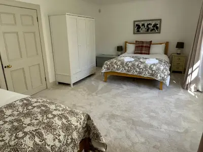 a bedroom with two beds and a white door at Underwood House Garden Flat in Kilmarnock