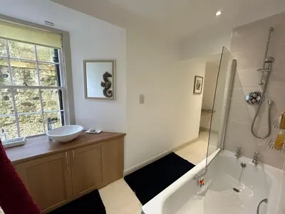 a bathroom with a tub and a sink and a shower at Underwood House Garden Flat in Kilmarnock