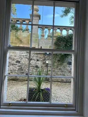 a window with a view of a stone fence at Underwood House Garden Flat in Kilmarnock
