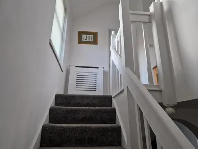 a stairway with white walls and a white stair case at Victoria Cottage in Whitrigg
